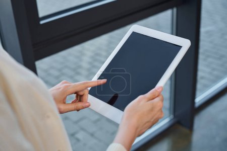 Eine Geschäftsfrau in einem modernen Büro hält selbstbewusst ein Tablet in der Hand und interagiert mit ihm, verkörpert das Franchise-Konzept.