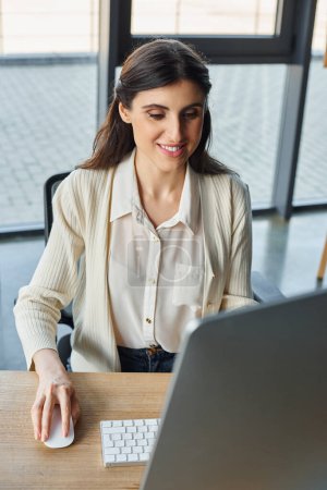 Une femme d'affaires immergée dans son travail dans un bureau moderne, utilisant un ordinateur pour naviguer dans les concepts de franchise.
