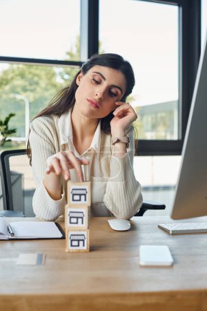 Une femme est assise à son bureau dans un bureau moderne, près de blocs empilés sur une table en bois, représentant le concept d'une franchise.