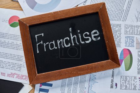 Photo for A blackboard with the word franchise written on it in bold chalk, symbolizing business expansion and growth in a modern office setting. - Royalty Free Image