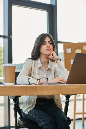 Una empresaria enfocada se sienta en una mesa con una laptop, rodeada por un moderno espacio de oficina, encarnando el concepto de franquicia.