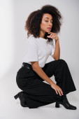 good looking african american female model sitting on floor and looking at camera, fashion concept magic mug #697415164