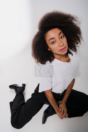 good looking african american female model sitting on floor and looking at camera, fashion concept tote bag #697415222