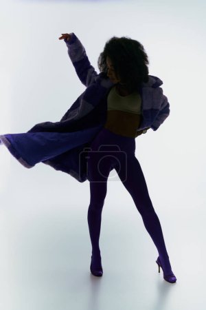 Foto de Modelo femenino afroamericano de moda en piel sintética de moda buscando camino en luces y sombras - Imagen libre de derechos