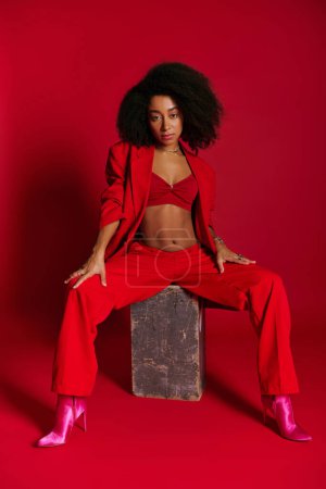 beautiful sexy african american woman in red attire sitting and looking at camera, fashion concept