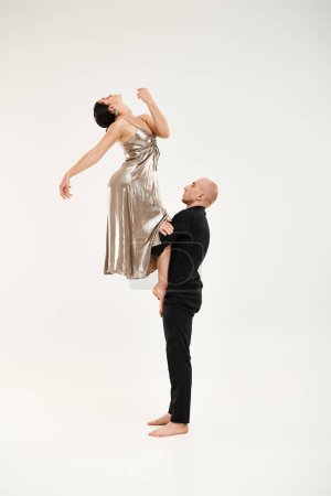 A young man and a woman in a silver dress engaging in a graceful dance routine, showcasing their synchronized movements and acrobatic skills.