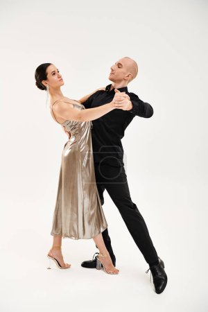 Ein junger Mann in Schwarz und eine junge Frau in einem Kleid führen in einem Studio gemeinsam akrobatische Tanzbewegungen auf.