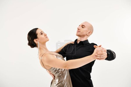 A young man in black and a young woman in a dress showcasing their dance moves in a mesmerizing studio shot.