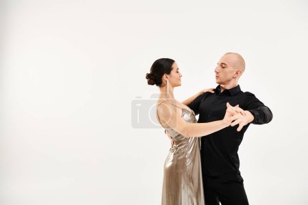 A young man in black attire and a young woman in a shiny dress dance fluidly.