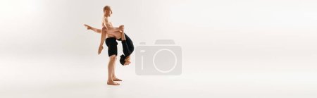 Photo for A shirtless young man and a woman dance with acrobatic grace while floating in the air against a white studio backdrop. - Royalty Free Image