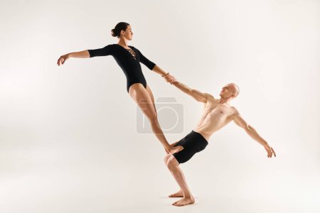 Shirtless young man and young woman execute acrobatic dance moves against a white backdrop.