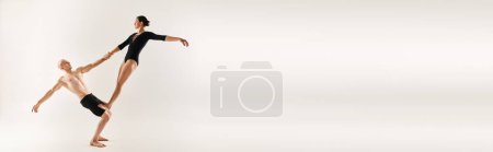 Téléchargez les photos : Un jeune homme torse nu et une jeune femme exécutent des éléments acrobatiques en plein air, présentant une routine de danse gracieuse et envoûtante. - en image libre de droit
