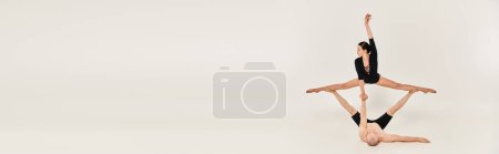 Photo for A shirtless young man and a dancing young woman performing acrobatic elements while standing in mid-air against a white background. - Royalty Free Image