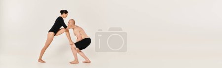 Shirtless young man and dancing young woman showcase acrobatic elements together in a studio shot on a white background.