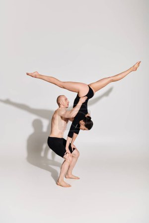 Un joven sin camisa y una mujer bailan y realizan elementos acrobáticos en un estudio sobre un fondo blanco.