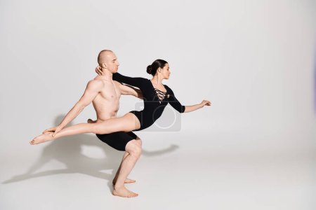 Téléchargez les photos : Un jeune homme torse nu et une jeune femme exécutent des mouvements de danse acrobatique en studio sur fond blanc. - en image libre de droit