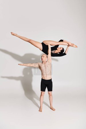 Shirtless young man and woman dance acrobatically in a studio on a white background.