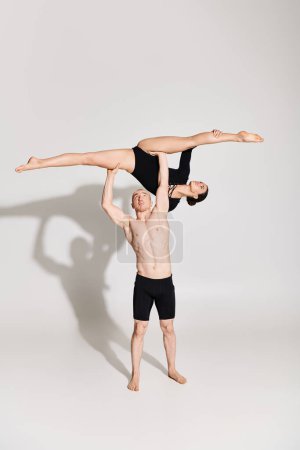 Shirtless young man and woman engage in synchronized handstand acrobatics, showcasing balance and strength.