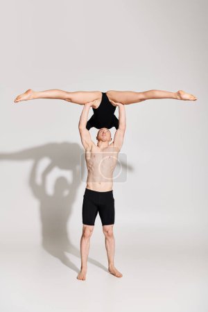 A man showcases incredible strength by holding a Woman above his head.