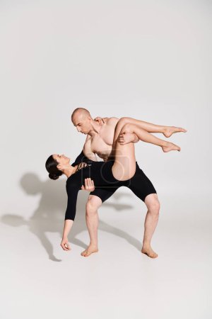 Hemdloser junger Mann und tanzende junge Frau in perfekter Harmonie in akrobatischer Pose vor weißem Hintergrund.