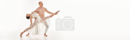 Foto de Un joven sin camisa y una mujer con un vestido blanco bailan con gracia, entrelazando y realizando movimientos acrobáticos en un entorno de estudio. - Imagen libre de derechos