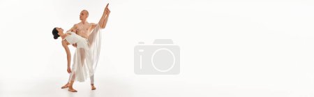 Foto de Un joven sin camisa y una mujer con un vestido blanco bailan con gracia y realizan elementos acrobáticos en un entorno de estudio. - Imagen libre de derechos