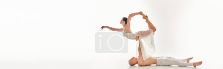 A shirtless young man and a woman in a white dress perform acrobatic dance moves.