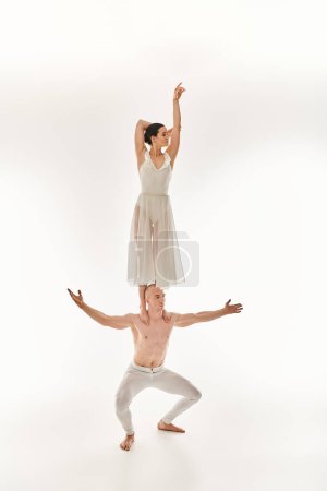 Shirtless young man and woman in white dress display acrobatic dance moves, studio shot.