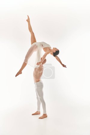 A shirtless young man and a woman in a white dress gracefully perform acrobatic dances in mid-air against a white backdrop.
