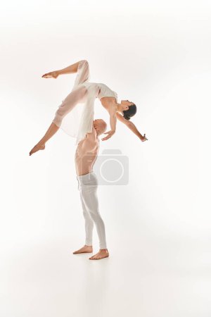A shirtless young man and a woman in a white dress showcasing their acrobatic skills.