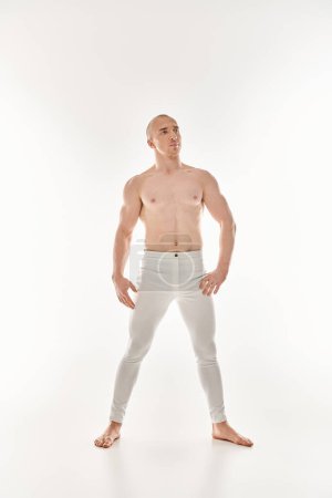 Téléchargez les photos : Un jeune homme en pantalon blanc frappe une pose dynamique, mettant en valeur des éléments acrobatiques sur un fond blanc. - en image libre de droit