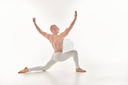 Ein junger Mann tanzt anmutig mit Präzision und Gleichgewicht in einem Studio auf weißem Hintergrund.