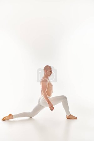 Ein junger Mann führt anmutig ein akrobatisches Element aus und präsentiert Ausgewogenheit und Gelassenheit in einem Studio vor weißem Hintergrund.