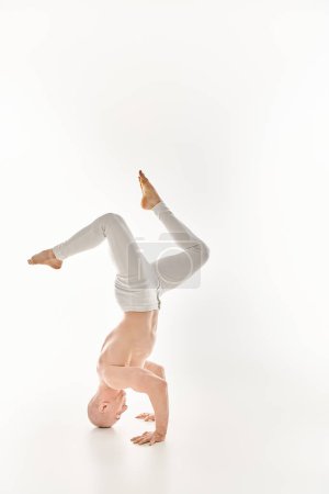 Photo for A man demonstrates strength and flexibility by performing a headstand. - Royalty Free Image