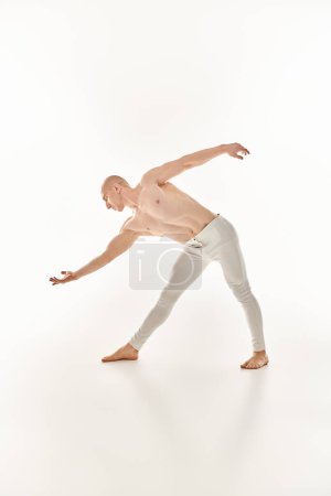 Ein junger Mann zeigt akrobatische Tanzbewegungen mit Präzision und Fließfähigkeit in einem Studio vor weißem Hintergrund.
