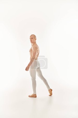 Foto de Un joven sin camisa muestra sus habilidades acrobáticas a través de la danza sobre un fondo blanco. - Imagen libre de derechos