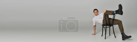 Photo for Sophisticated man in trendy attire sitting on chair and looking away on gray backdrop, banner - Royalty Free Image