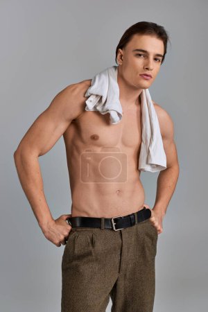 Foto de Sexy joven con camiseta en el hombro posando en topless y mirando a la cámara en el fondo gris - Imagen libre de derechos