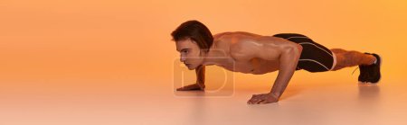 Photo for Young shirtless man in black shorts exercising actively and looking away on orange backdrop, banner - Royalty Free Image