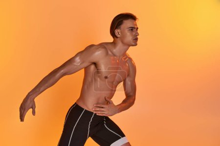 good looking young athletic man posing topless in active motions on orange vivid background