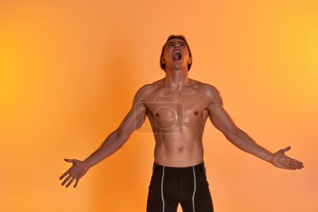 attractive young shirtless man expressing himself emotionally while on vibrant orange backdrop