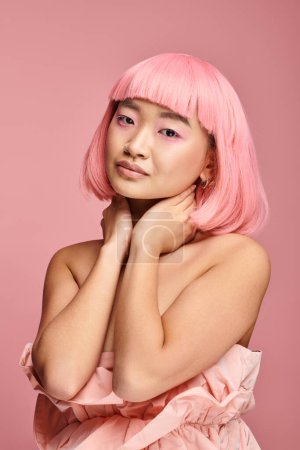 Téléchargez les photos : Portrait de charmante femme aux cheveux roses et maquillage touchant le cou avec les mains sur fond vibrant - en image libre de droit
