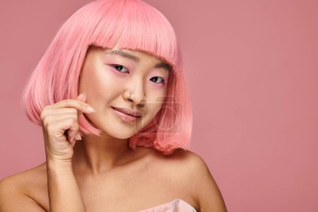 Téléchargez les photos : Charmante asiatique jeune femme avec nez piercing montrant coeur signe et sourire dans vibrant fond - en image libre de droit