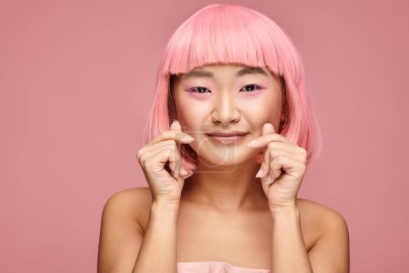 Téléchargez les photos : Belle asiatique jeune femme avec rose cheveux montrant avec mains coeur signe sur fond vibrant - en image libre de droit