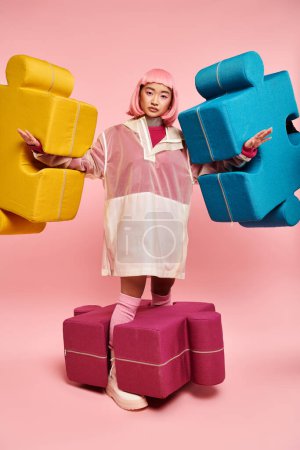 Photo for Attractive young woman with pink hair posing with larges puzzles against vibrant background - Royalty Free Image