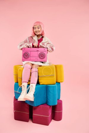 hermosa mujer asiática con pelo rosa sentado en grandes puzzles con boombox sobre fondo vibrante