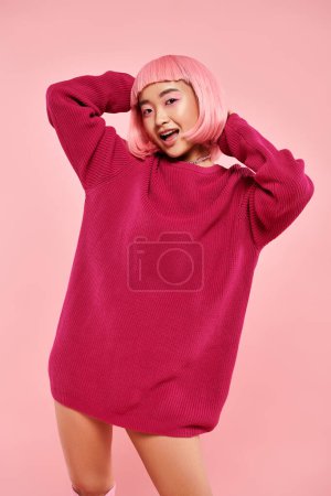 süße asiatische junge Frau mit rosa Haaren und Make-up im großen Pullover vor lebendigem Hintergrund