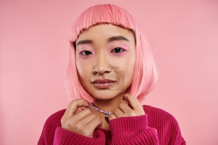 close up of beautiful asian young woman with pearl necklace, pink hair and makeup looking to camera