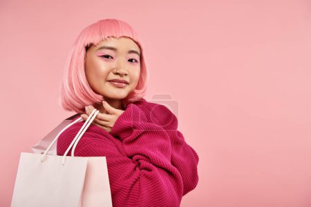 hermosa mujer asiática en 20s con pelo rosa y maquillaje posando con paquetes sobre fondo vibrante