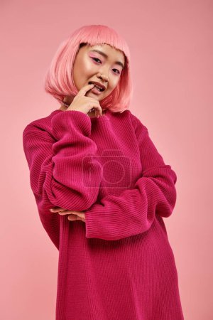 hübsche junge Frau mit rosa Haaren posiert und beißt Nagel vor lebendigem Hintergrund